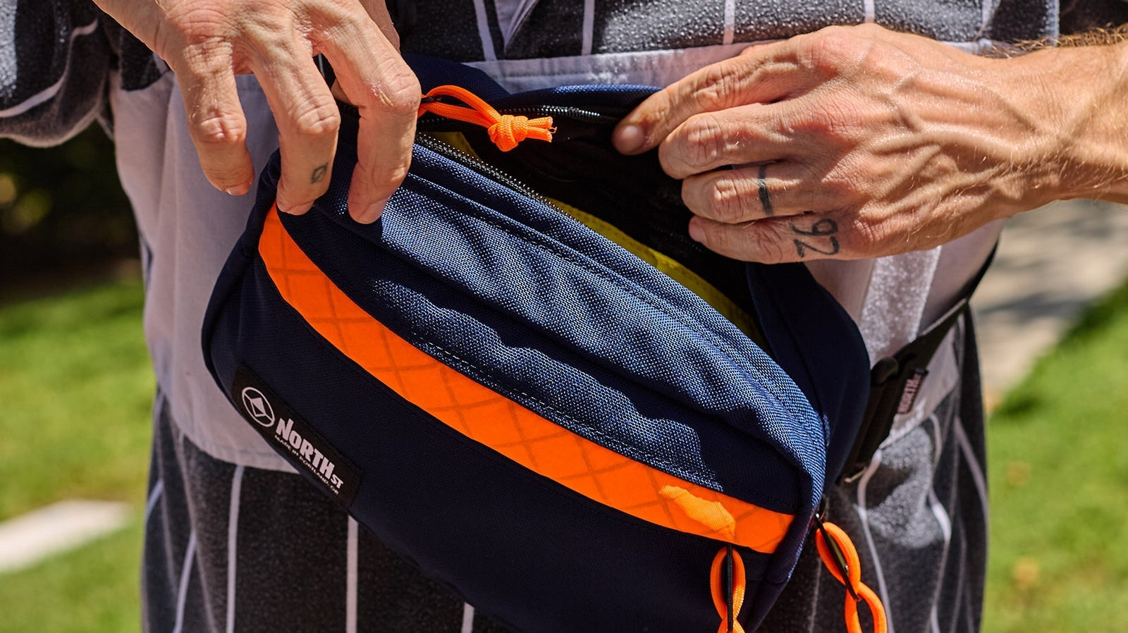 man opening up a blue and orange sling pack