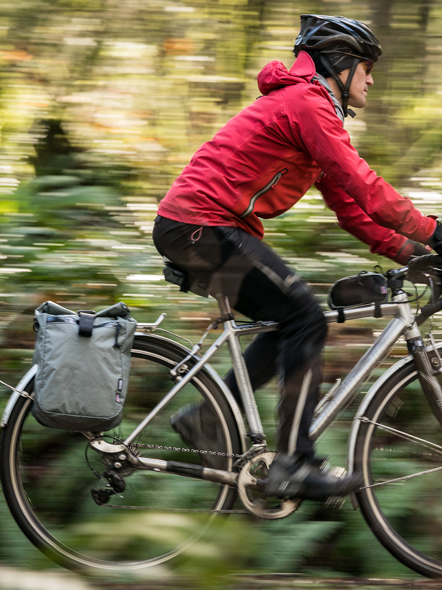 Cyclist riding through the woods with a gray pannier - North St Bags all-groups