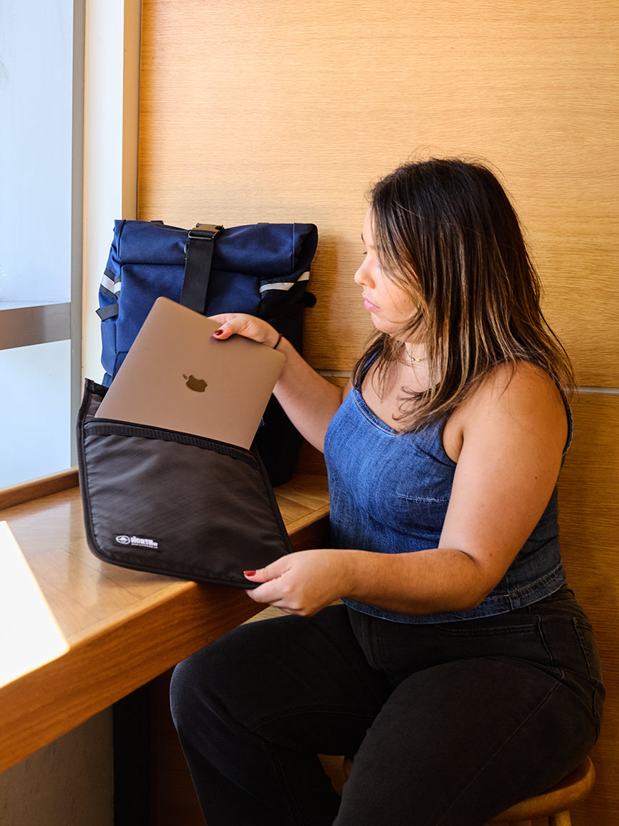 Woman sitting at a desk with a laptop, laptop sleeve and bags in a coffee shop. all-groups