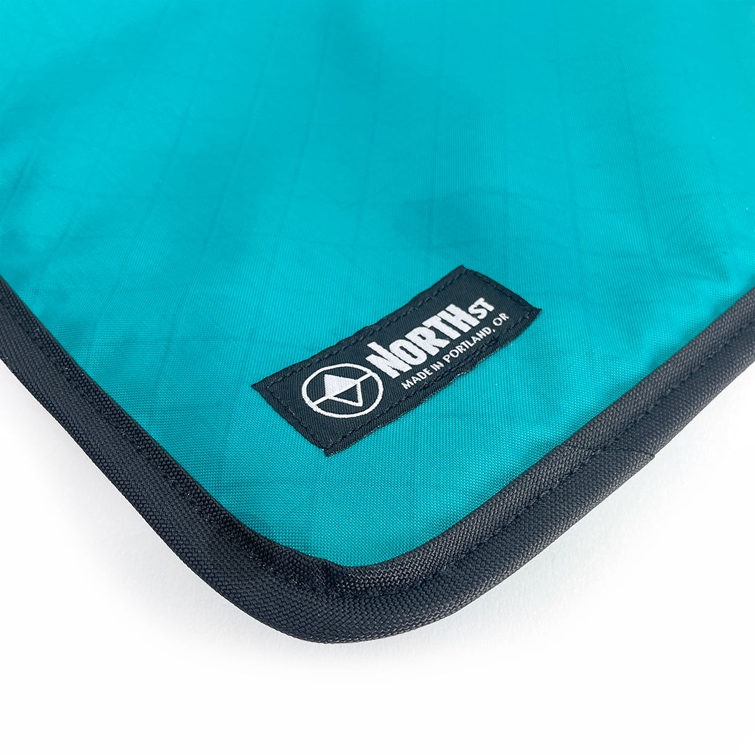Teal laptop sleeve with North St Label visible