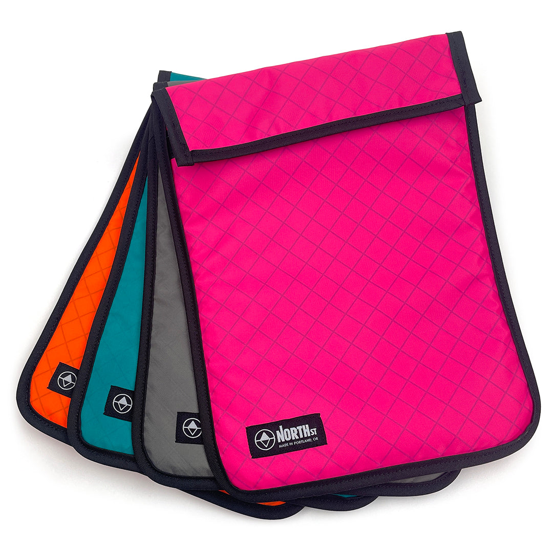 Four padded laptop sleeves in an array of colors showing North St label. all-groups