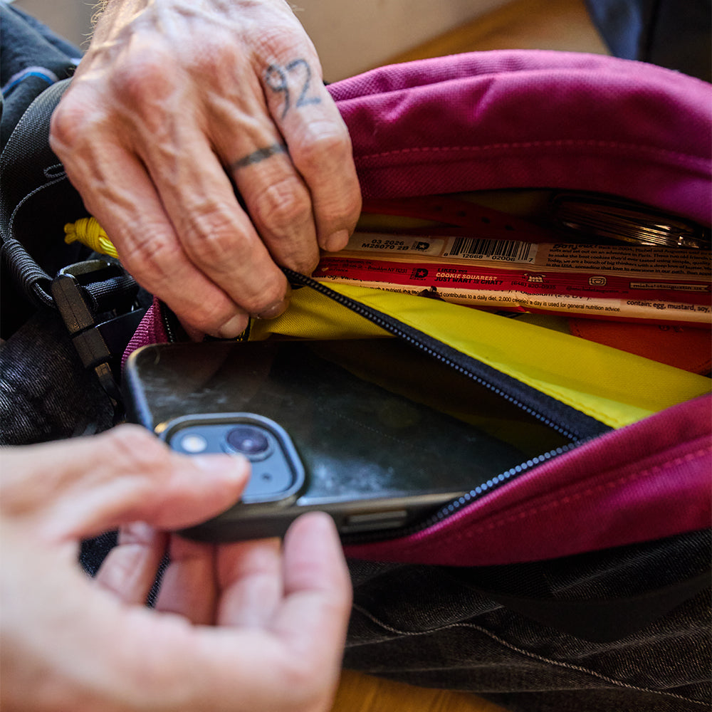 Person reaching into a burgundy bag to retrieve a smartphone all-groups