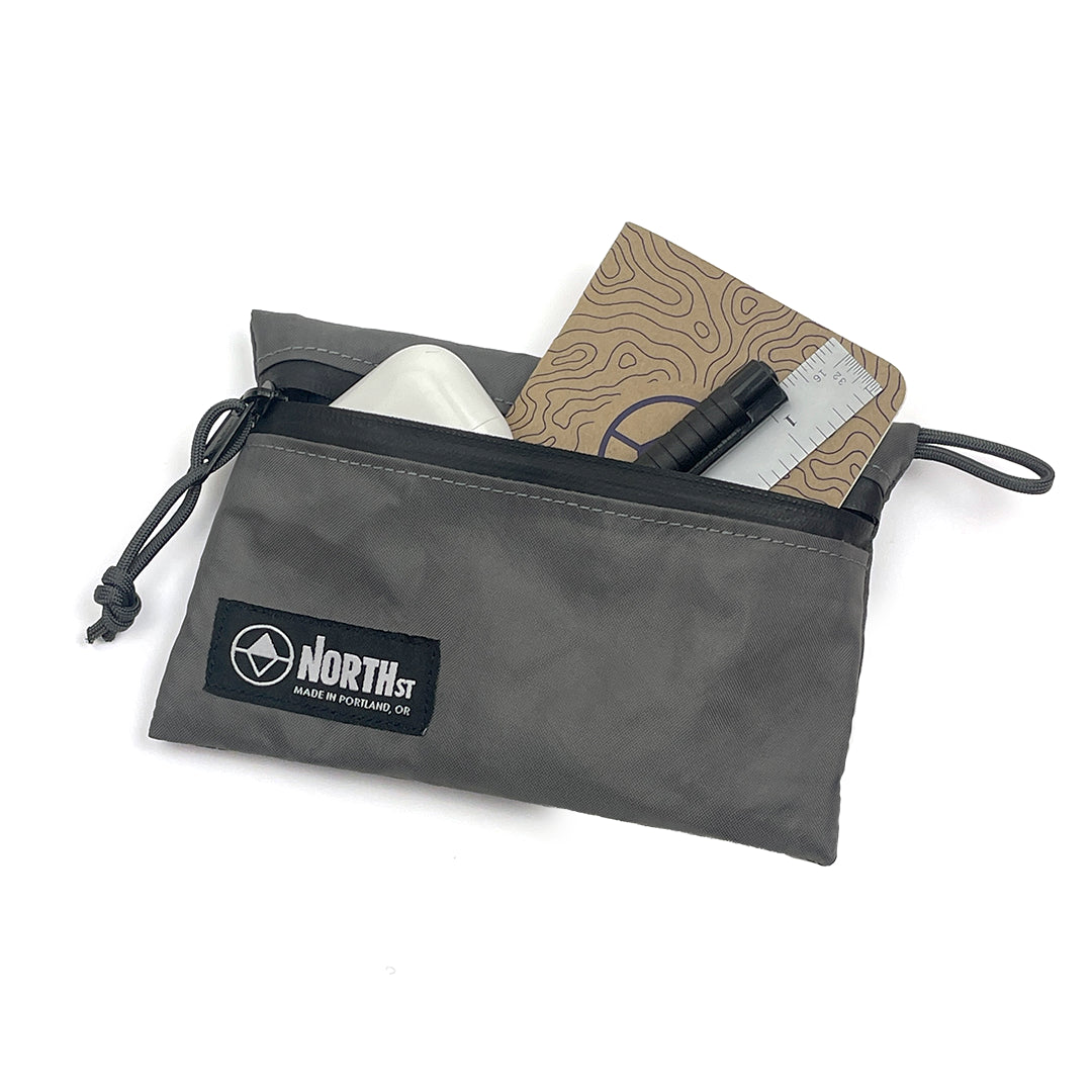 Gray pouch with a North St. label containing a notebook, ruler, and other items on a white background. all-groups