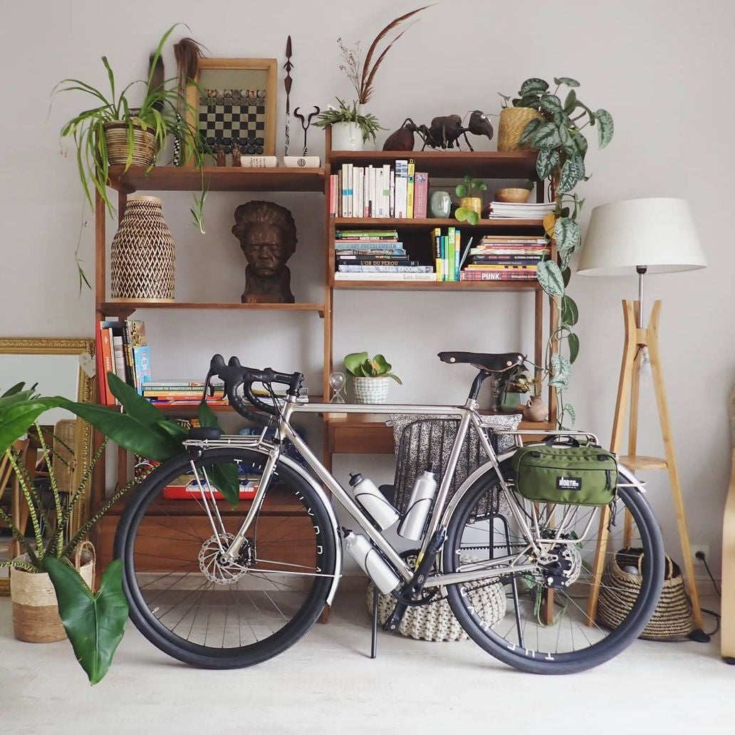 Bike leaning up against shelves in a stylish apartment.
