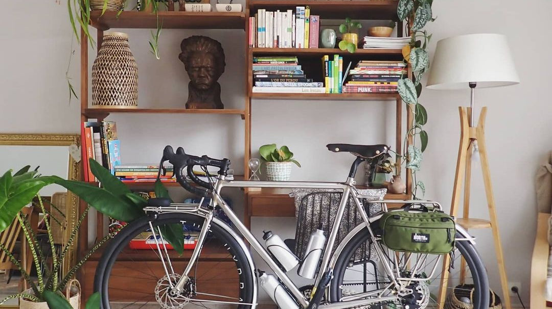 Bike leaning up against shelves in a stylish apartment.