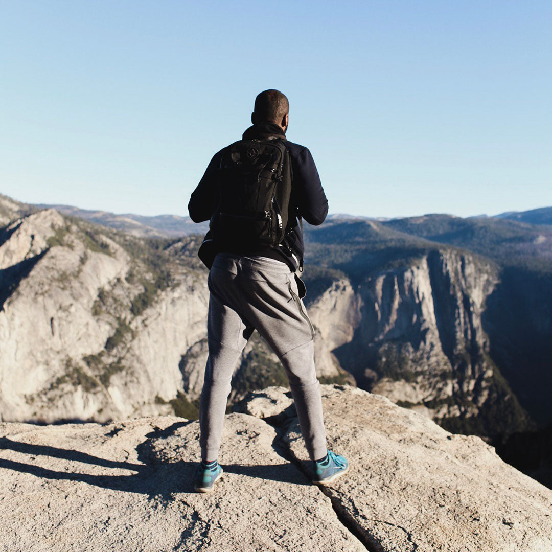 man at a mountain summit wearing travel backpack