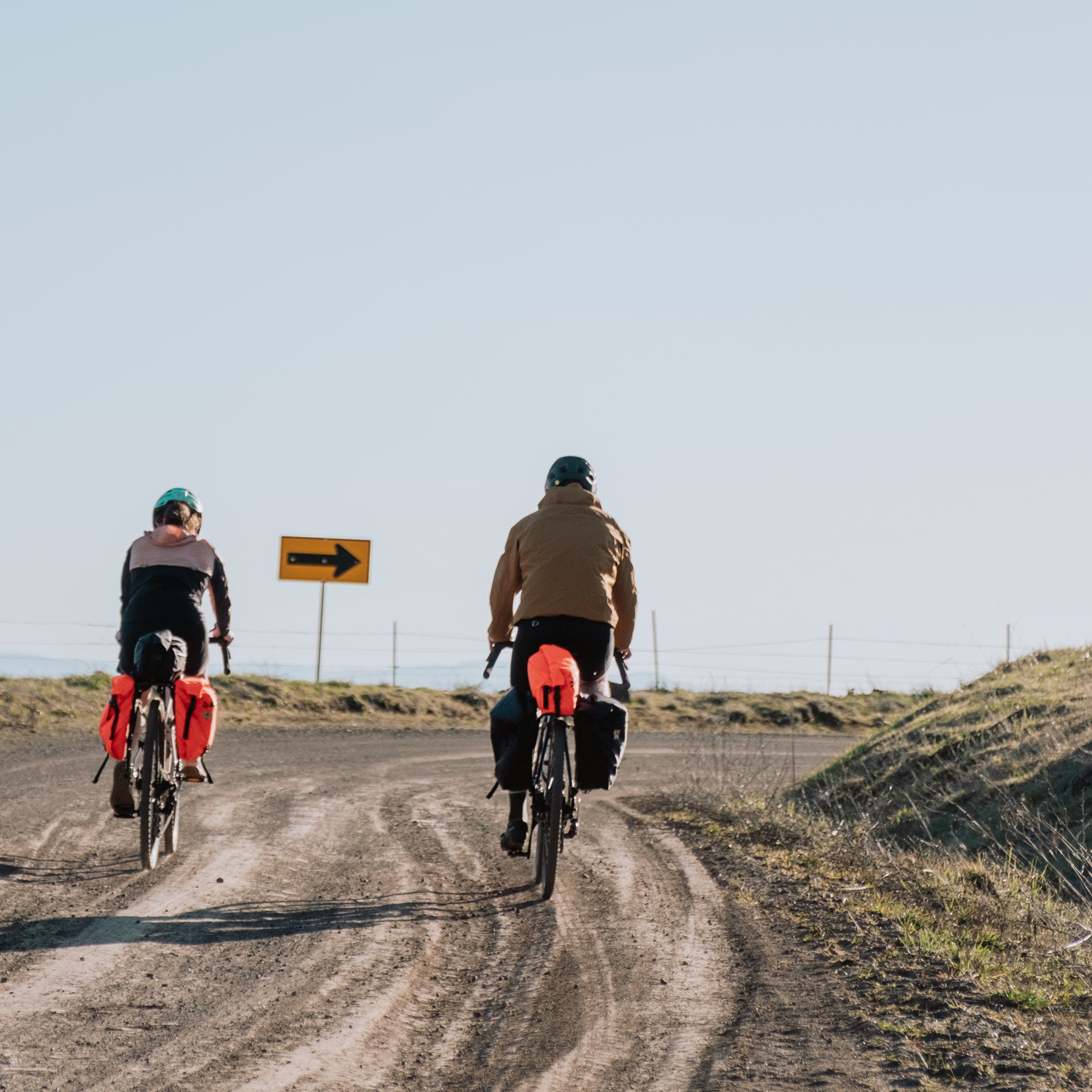 two cyclists riding on a gravel road with bikepacking bags