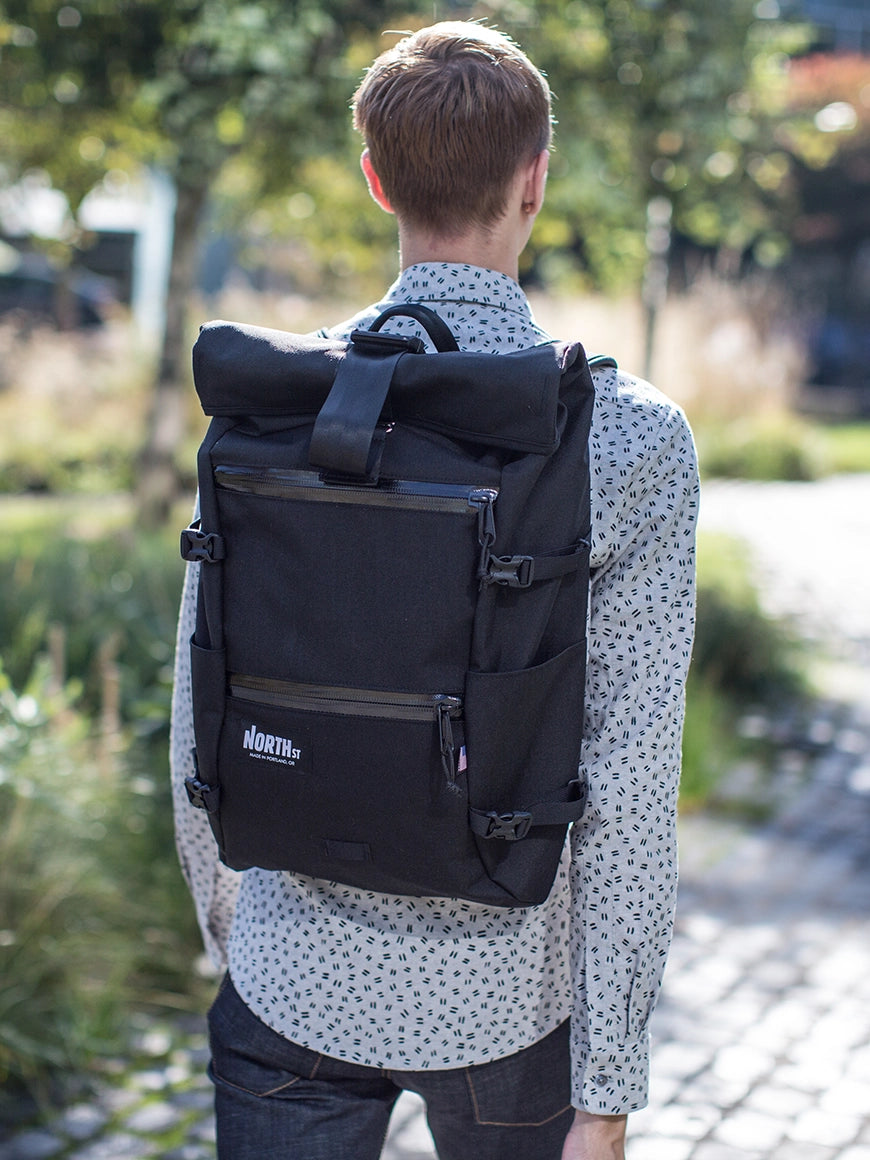 Guy walking in park wearing a black  Flanders Backpack. | North St Bags - all-groups
