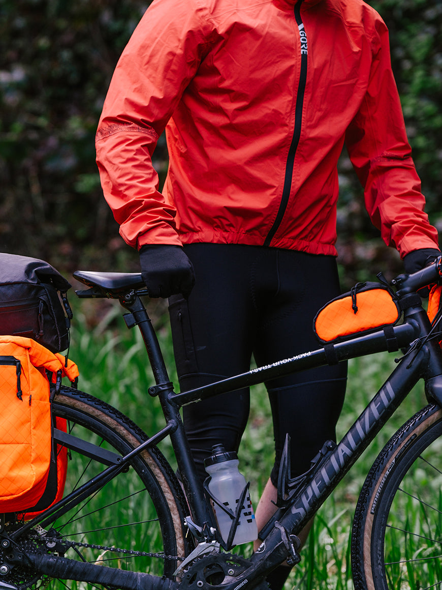 Man walking a bike on a wet rainy trail with bikepacking bags. - North St Bags all-groups