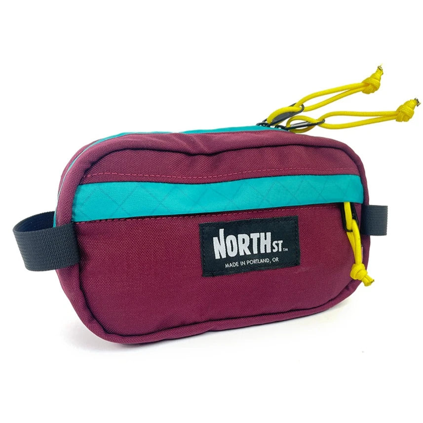 Front view of Pioneer 9 Hip Pack in burgundy and teal. - North St. Bags