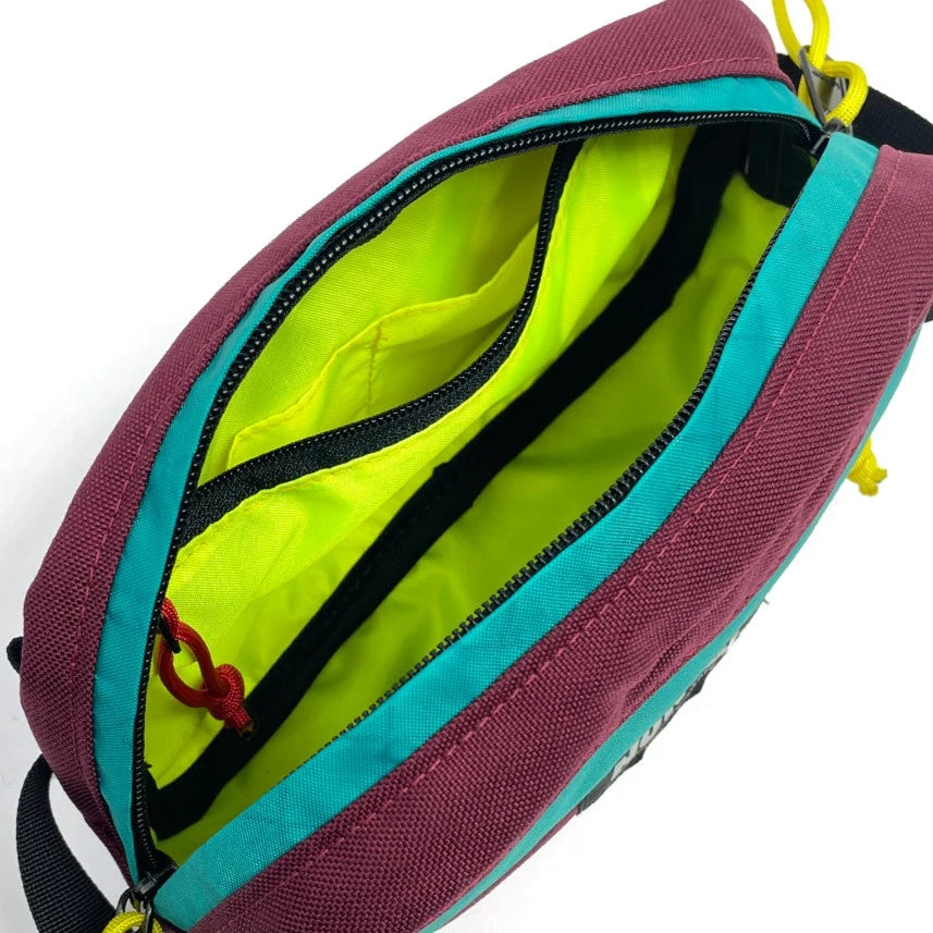 Interior view of Pioneer 9 Hip Pack in burgundy and teal with yellow liner. - North St. Bags