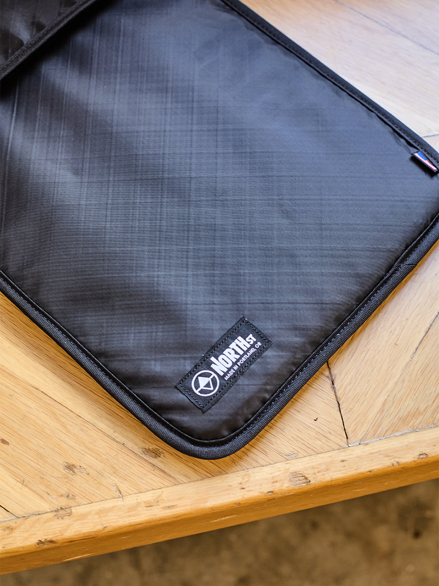 Black laptop sleeve on a wooden bench. all-groups