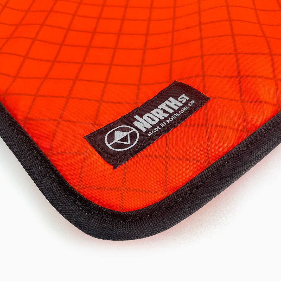 Orange laptop sleeve with North St Label visible