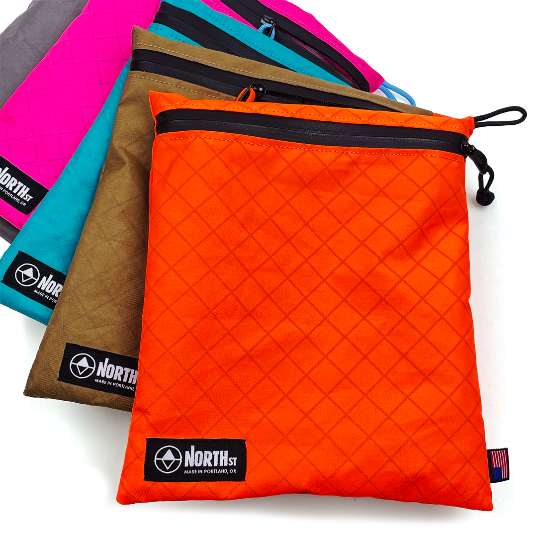 Large zipper pouches with visible brand in an array of color. all-groups