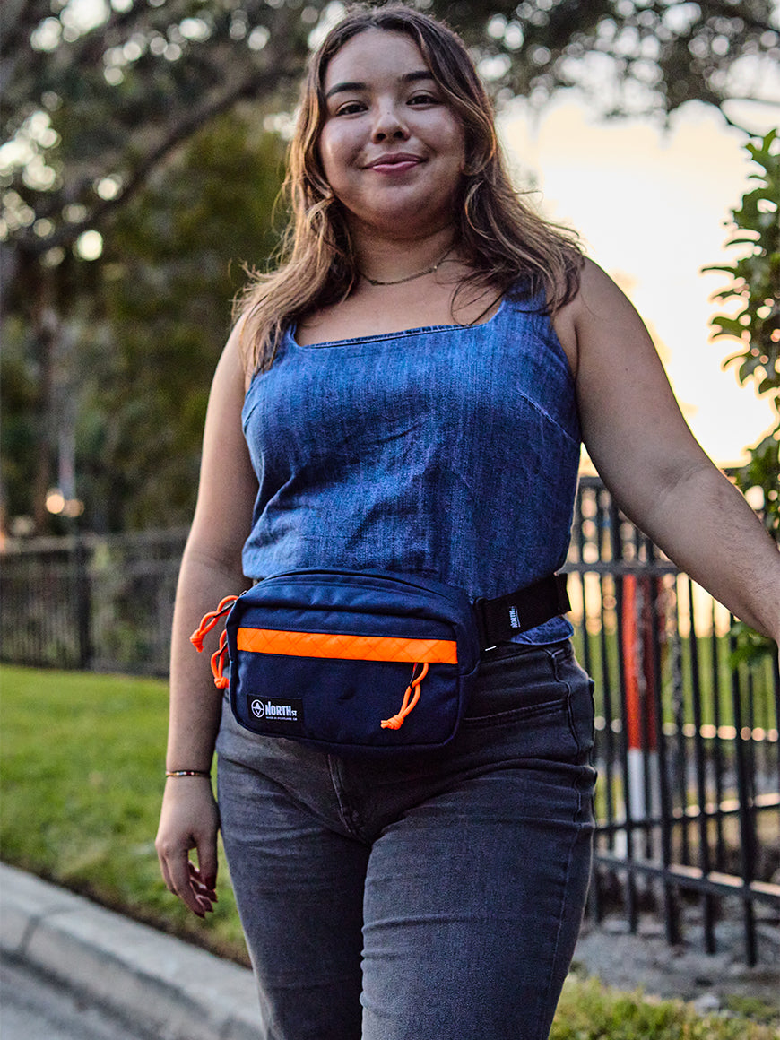 Woman wearing a blue tank top and orange waist bag outdoors