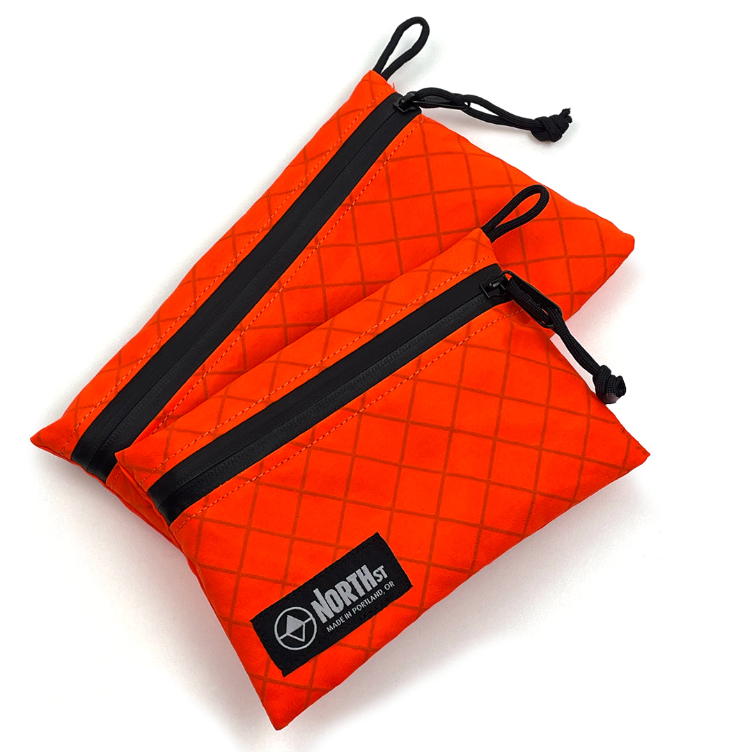 Orange Travel Pouch with Black drawstirings and visible logo on white backtround