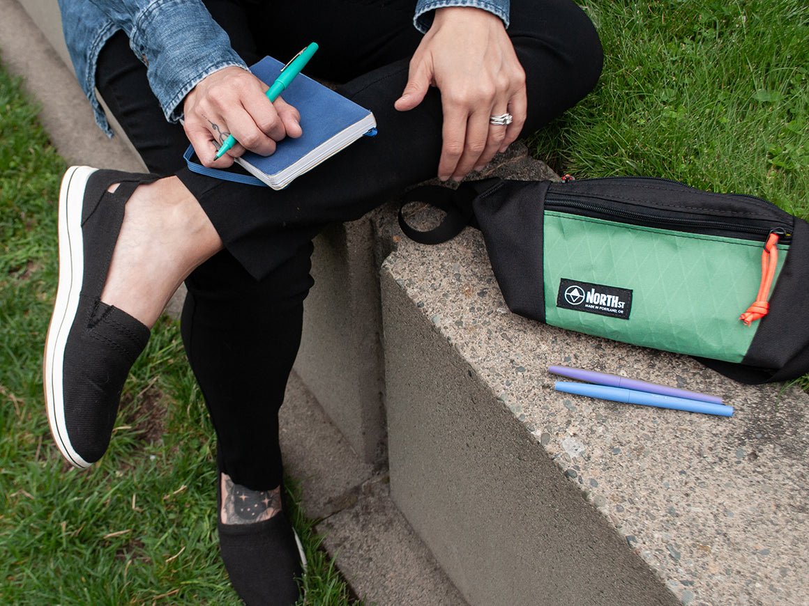 woman with journal sitting in a park with a sling pack - North St Bags - all-groupsl