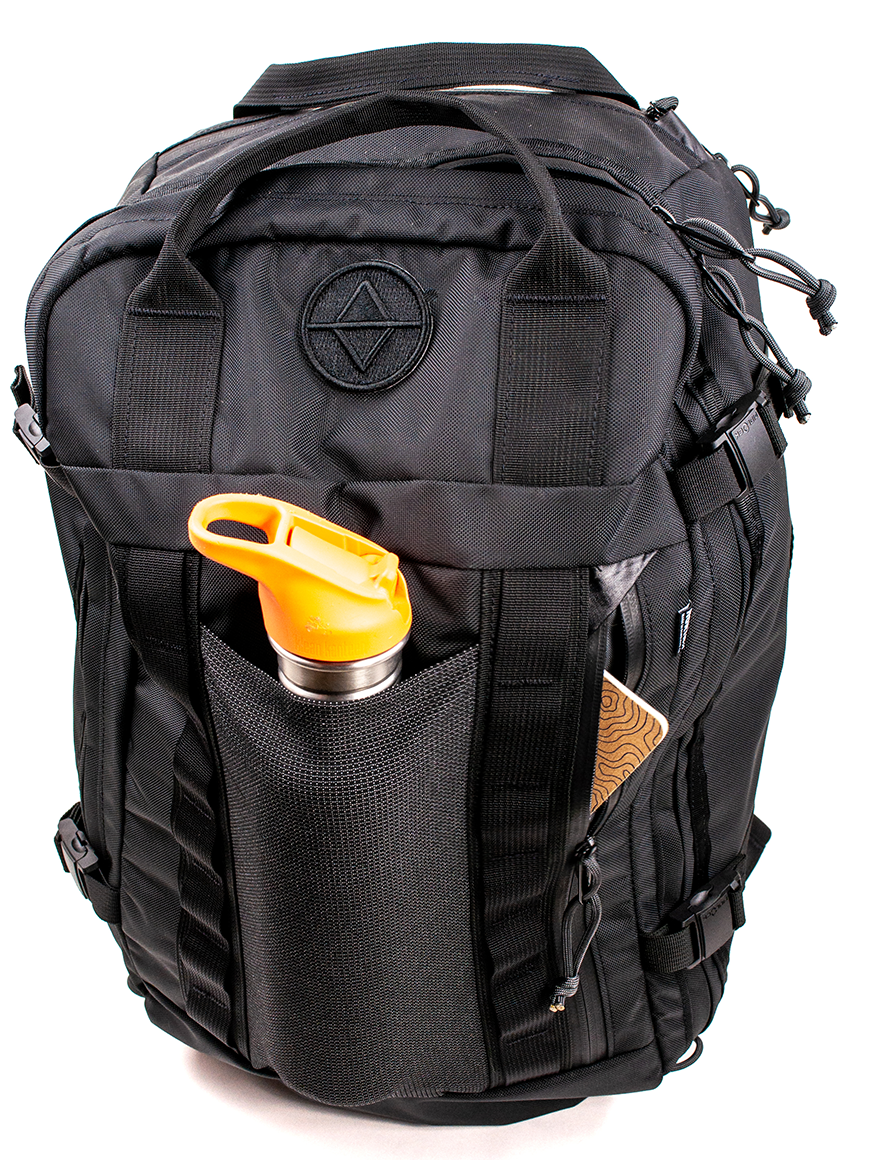 Detail view of a black travel backpack showing water bottle sleeve and front zipper pocket on a white backrgound. 