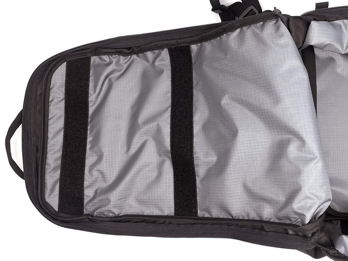 Close-up of the interior of a black and gray backpack, showing a gray liner with two black vertical velcro rows and black zipper trim.