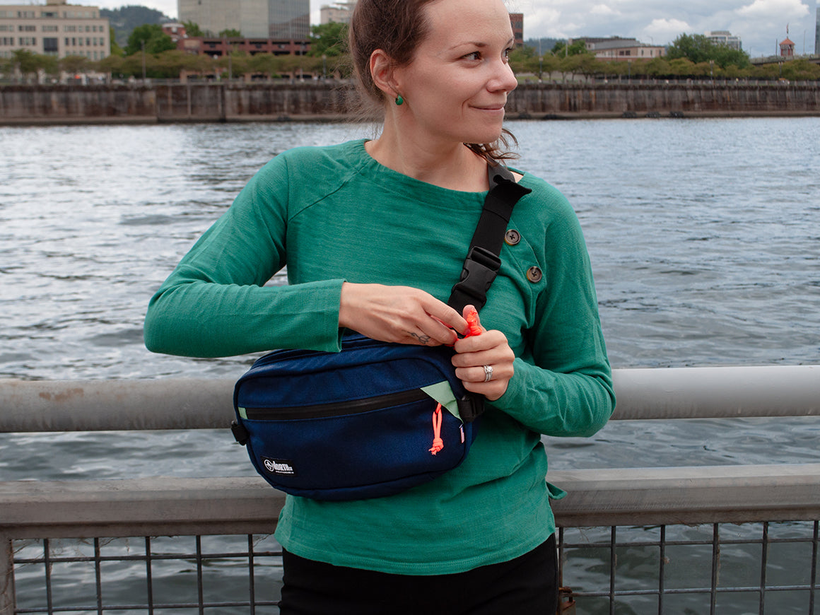 woman at waterfront opening a sling pack North St Bags all-groups