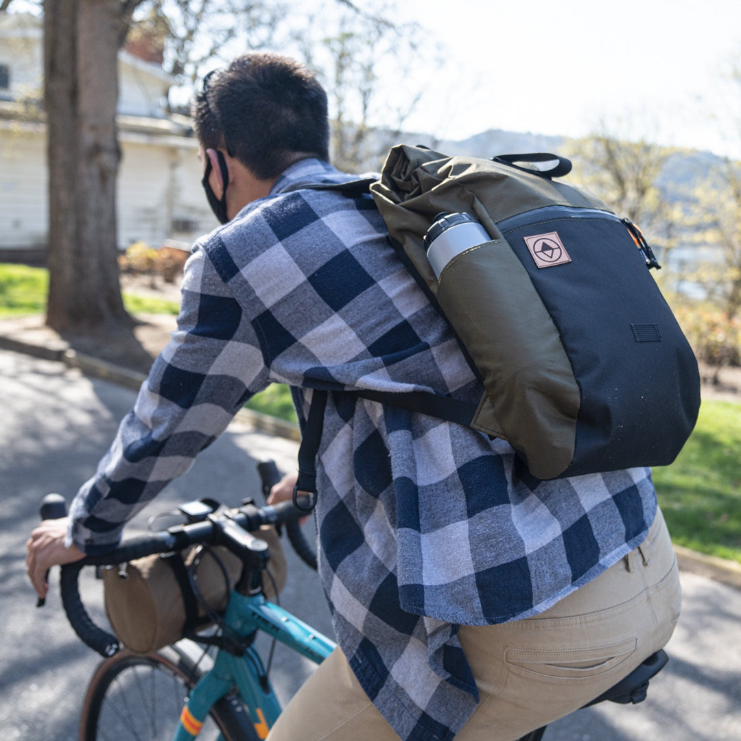 Guy riding bike through a park with a Davis Daypack - North St. Bags all-groups