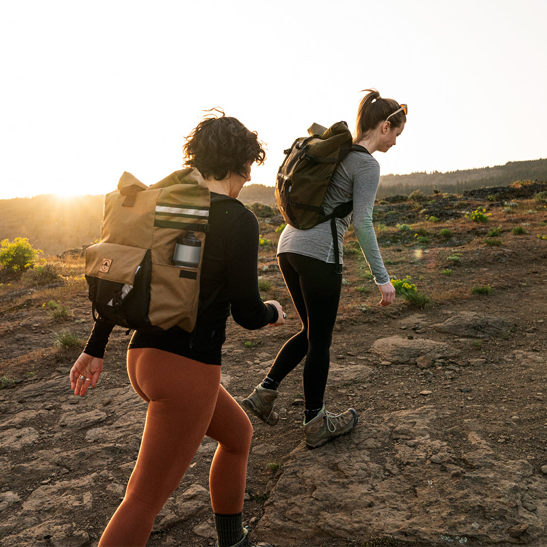 Two women hiking on a mountain trail. One is wearing a Woodward backpack pannier. - North St. Bags all-groups
